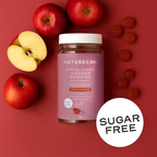 Naturecan Apple Cider Vinegar Gummies lifestyle – jar on red background surrounded by fresh red apples and pink gummies, sugar free label