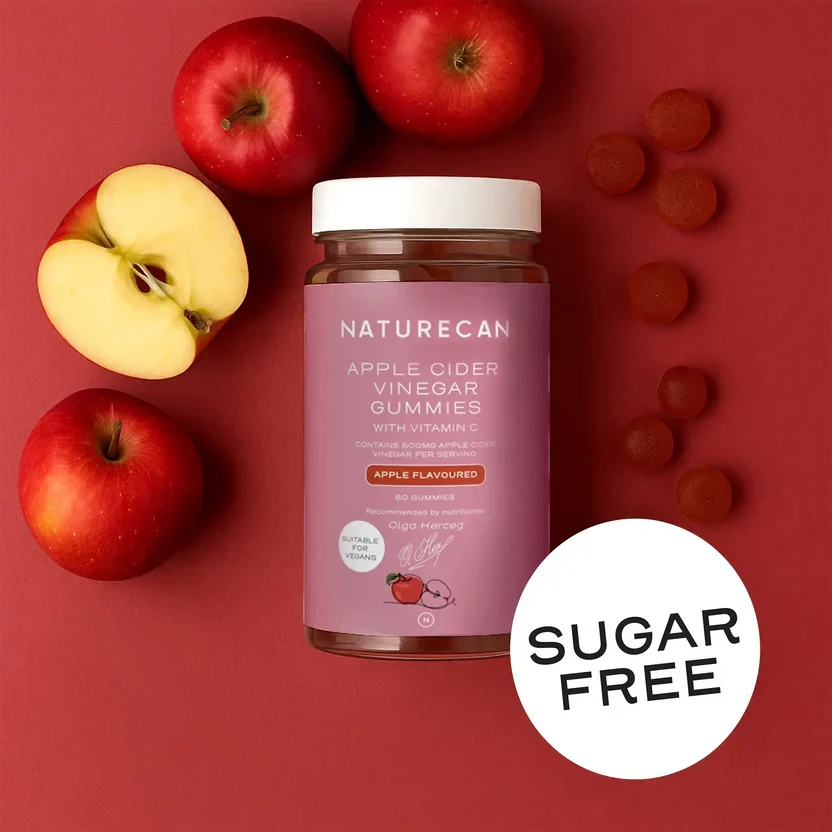 Naturecan Apple Cider Vinegar Gummies lifestyle – jar on red background surrounded by fresh red apples and pink gummies, sugar free label